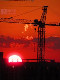 the sun is setting behind a construction crane