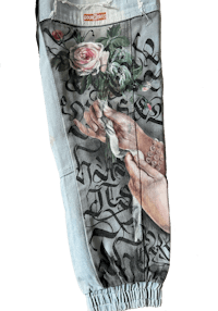 a pair of jeans with a painting of a hand holding a rose