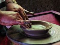 a person is making a bowl on a pottery wheel