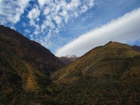 a valley with mountains and clouds under a blue sky